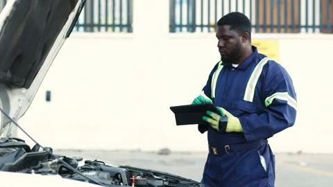African mechanic uses smart tablet for engine diagnostics in workshop Stock Footage 346641476