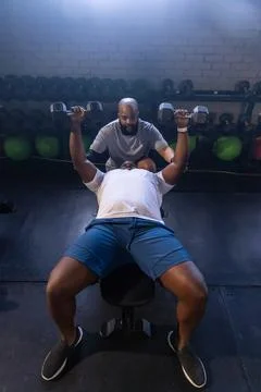 African men, lifter in white tee shorts doing hex dumbbell press on flat bench, Stock Photos