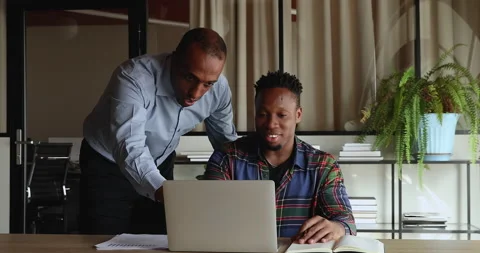 African mentor explain software, provide professional guidance to young intern Stock Footage 157717376