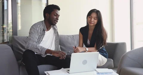 African mentor explaining online project to asian intern with laptop Stock Footage 131973474