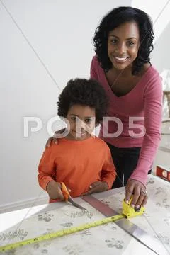 African mother teaching son to measure wallpaper Stock Photos