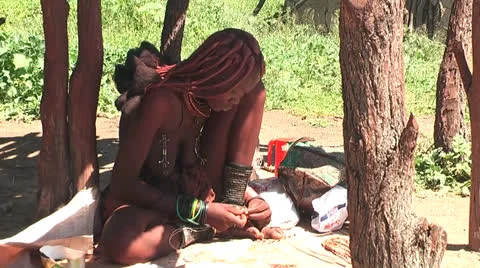 African native tribes - Young Himba girl producing jewelery in Namibia Video stock 26929433