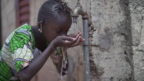 African Schoolgirl drinking Safe Water from Tap Outdoors in Bamako Stock Footage