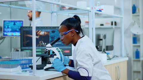 African scientist checking sample of virus using microscope Stock Photos