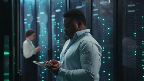African smart administrator examining operational server rack cabinets with Stock Footage 119736590