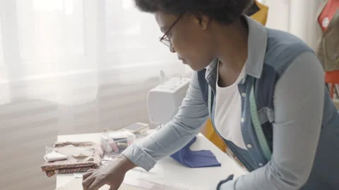 African tailor making notes on sewing pattern, fashion brand, clothing industry Stock Footage 153986043