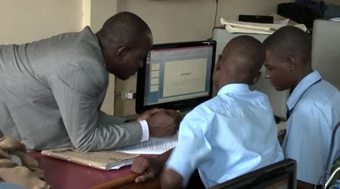 African teacher help school students in computer class-writing article internet Video stock 58975687