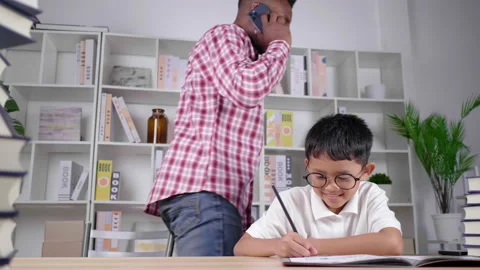 African teacher is teaching a boy a lesson at home. Incoming call interrupts  Video stock 165437462