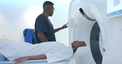 African tech adjusting patient head on CT table following lasers aligning, Stock Footage 336305939