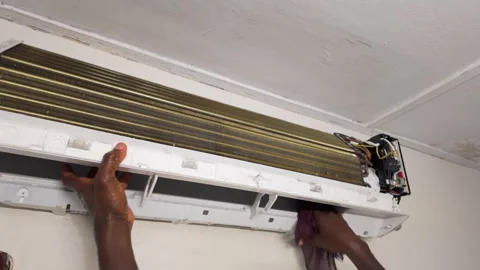 African technician cleaning and maintaining wall-mounted air conditioner blower Video stock 346004677