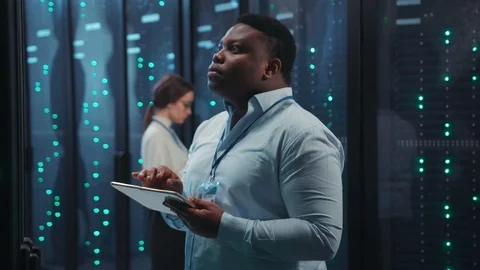 African technician in data center checking working server rack in digital room Stock Footage 119782216