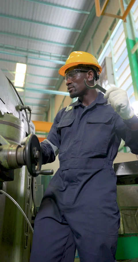 African technician operates drill press in vertical frame, holding wrench near Stock Footage 332908098