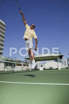 African tennis player jumping with racket Stock Photos