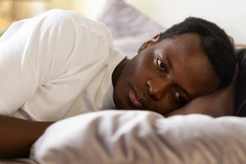 African tired man cannot sleep from insomnia Stock Photos
