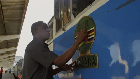 African train driver wiping the sign on the train, DaresSalaam Tanzania Stock Footage 132196554