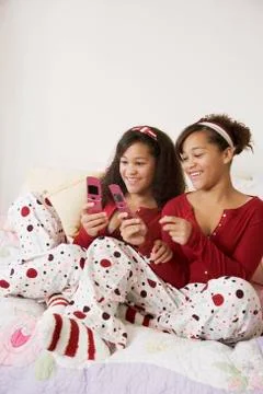 African twin sisters looking at cell phones Stock Photos