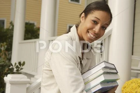 African woman carrying stack of books Stock Photos