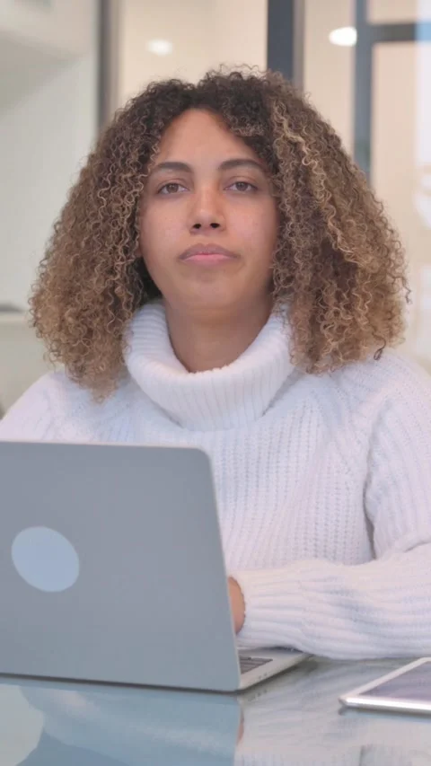 African Woman Looking at Camera while Working on Laptop in Office, Vertical 스톡 동영상 321110343