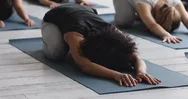 African Woman Performing Child Pose With Associates During Yoga Class Stock Footage