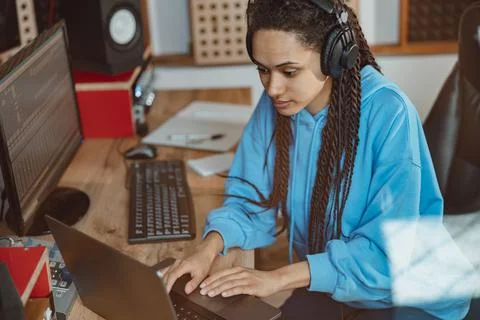 African woman, radio presenter, sound engineer in headphones typing text on Stock Photos