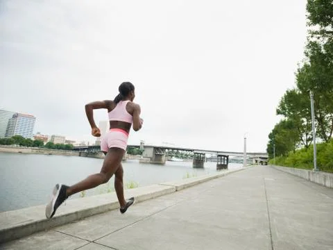 African woman running along urban waterfront Stock Photos