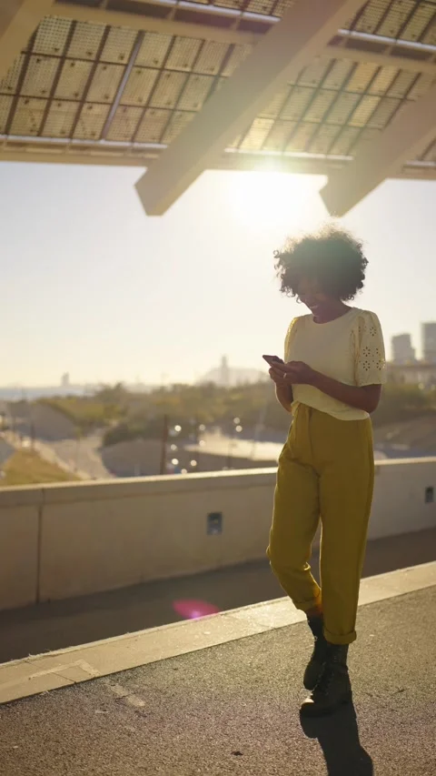 African woman smiling while using phone walking along the city Stock Footage 260194957