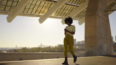 African woman smiling while using phone walking along the city Stock Footage 262604320