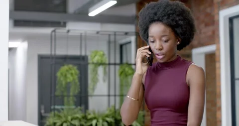 African woman taking call while pointing at parcel in reception confirming Stock Footage 341991165