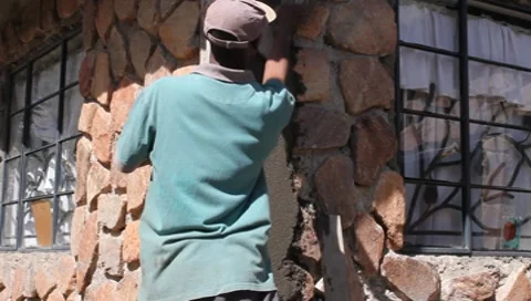 African Worker Plastering Corner of Stone House  (HD) Stock Footage 8830634