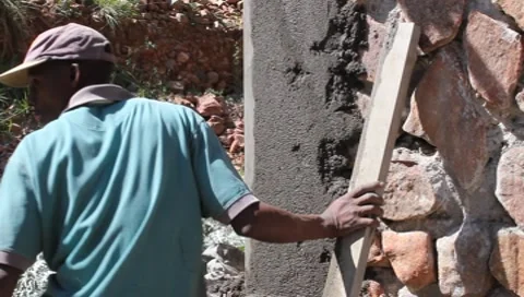 African Worker Plastering Stone Wall  (HD) Stock Footage 8830600