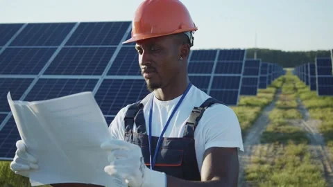 African young engineer in hard hat learning the paper plan construction of solar Stock Footage 135700620