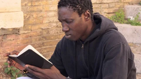 African young handsome man writing notes on his agenda on steps. Close up Video stock 217802653