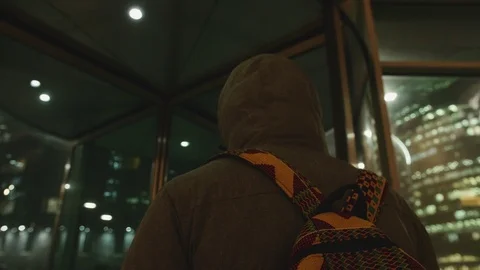 African young man in a jacket walks into a revolving door. He has a backpack on  Stock Footage 102437482