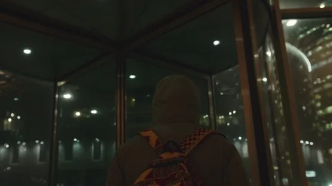 African young man in a jacket walks into a revolving door. He has a backpack on Stock Footage 102437520