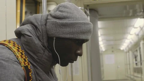 African young man riding the empty subway, listening to music with headphones Stock Footage 102438030