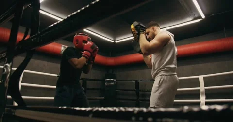 Afro American boxer in gloves is training with a coach in the boxing ring Stock Footage 275277032