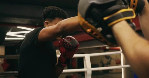 Afro American boxer in gloves is training with a coach in the boxing ring Video stock 275277458