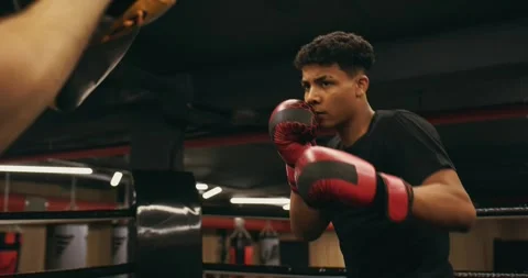 Afro American boxer in gloves is training with a coach in the boxing ring Stock Footage 275277643