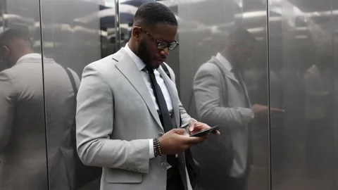 Afro-American Business Man Using A Mobile Phone In Elevator. Company Lift Stock Footage 238805240