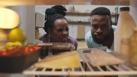 Afro-american couple opening fridge and wrinkling face having food spoiled Stock Footage