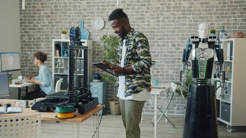 Afro-American engineer making 3d part for robot using three-dimensional printer Stock Footage 119557932