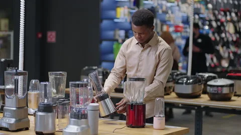 Afro-american guy is choosing blender in kitchen appliances store, single man is Stock Footage 153132500