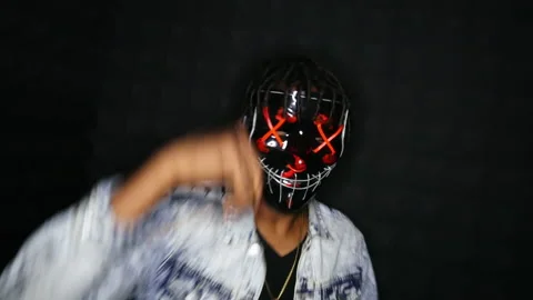 Afro-American guy dancing to rapper music in mask in the dark room Stock Footage 142443991