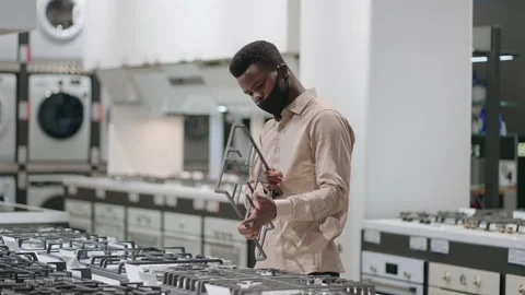 Afro-american guy is examining cooker in home appliances store, single man is Stock Footage 153016060
