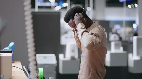 Afro-american guy is testing modern headphones in audio equipment store, medium Vídeos de archivo 153073465