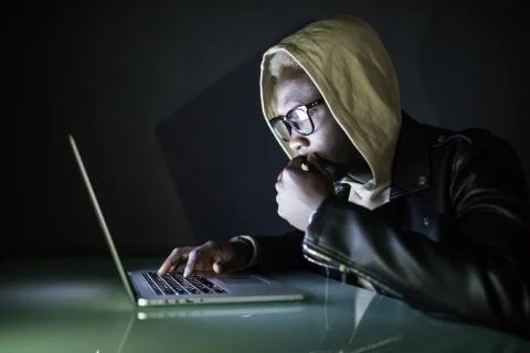 Afro american Hacker in Hood using Laptop Computer in the Dark hack networks  Stock Photos