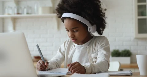 Afro american kid girl wearing headphones studying online from home Stock Footage