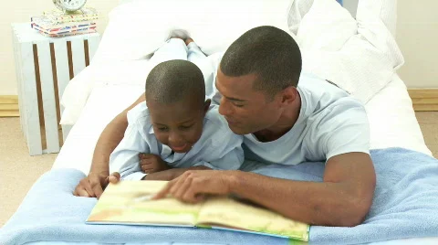 Afro-American little boy rand his father reading a book in bedroom Stock Footage