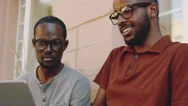 Afro-American Male Friends Using Laptop And Smiling Outdoors Stock Footage