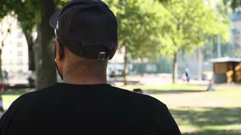 Afro american man with a black cap standing in a park from behind Stock Footage 140187032